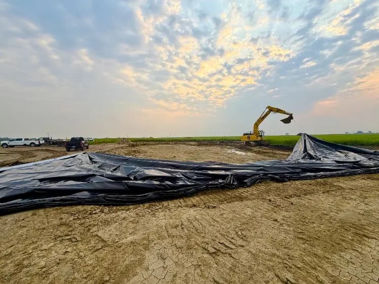 Geomembrane liner laid out across the excavation at Aarhus 4-12 under an evening sky.