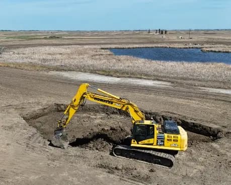 An excavator works the cut at Nelson State 1 alongside open water.